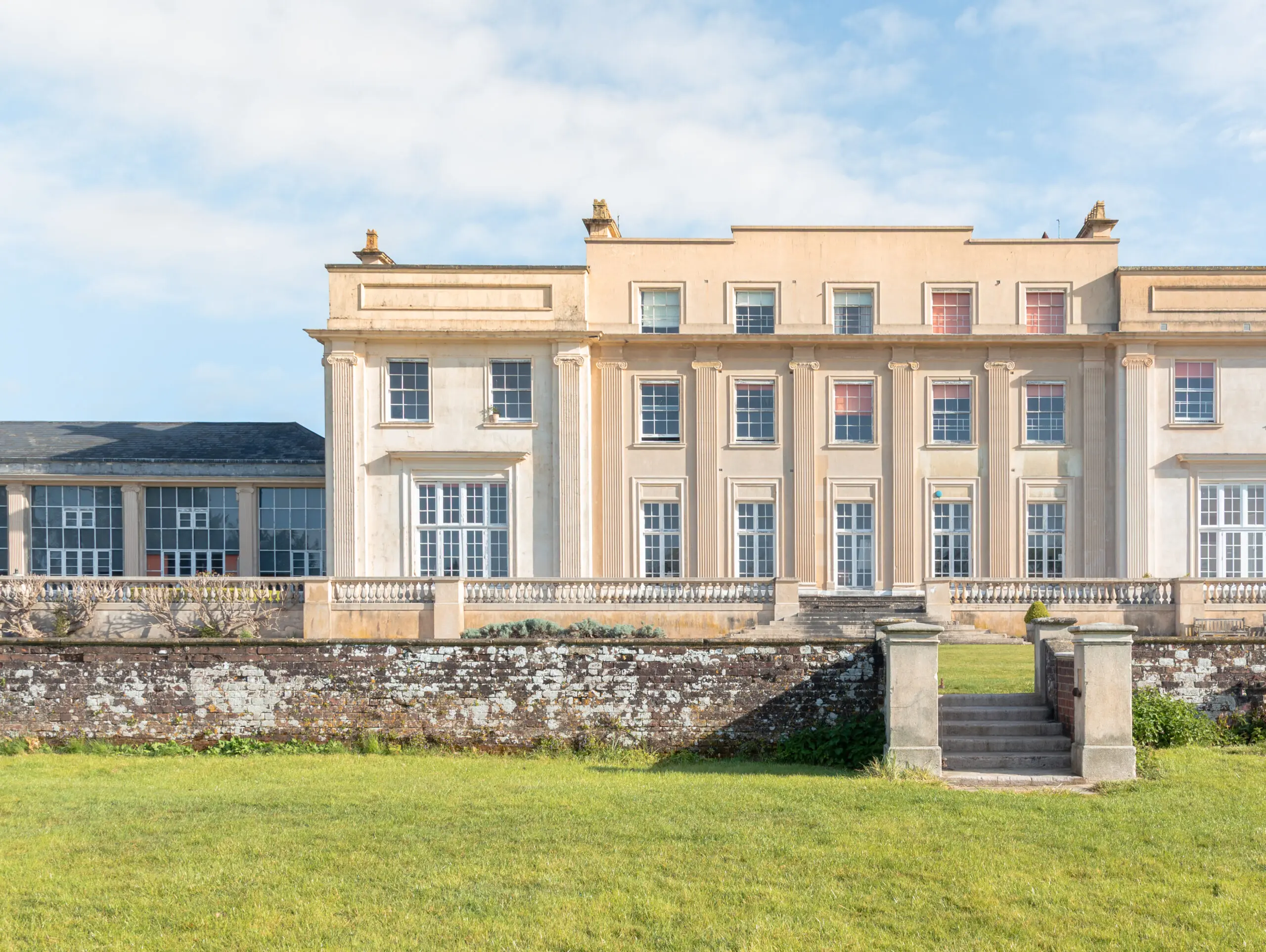 Georgian country house facade with Ionic columns, stone balustrade and garden steps